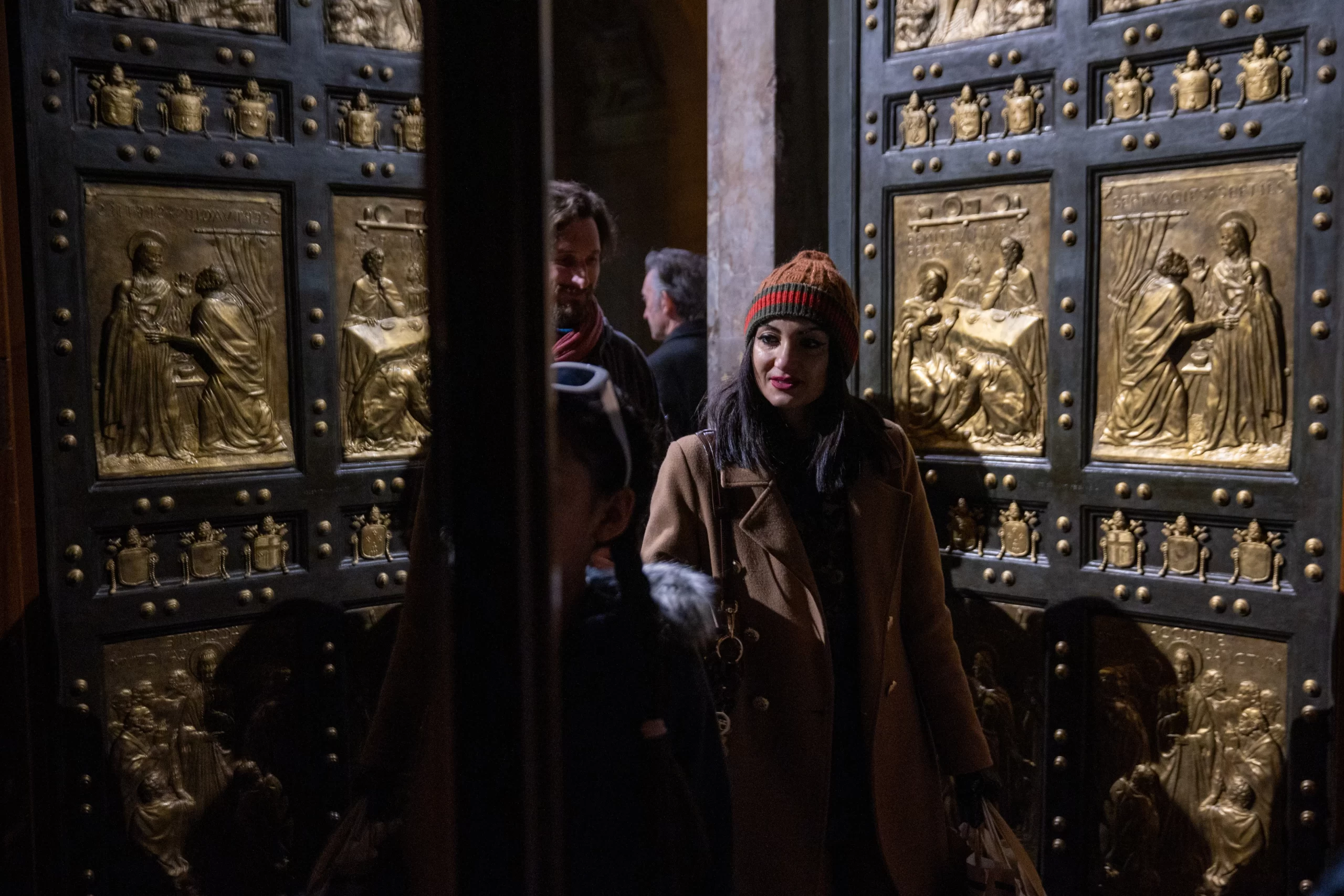 A visitor admires the bronze panels of the Holy Door at St. Peter's Basilica, specially illuminated for the 'White Night' celebration of the Jubilee of Artists, Feb. 16, 2025. Credit: Daniel Ibáñez/CNA