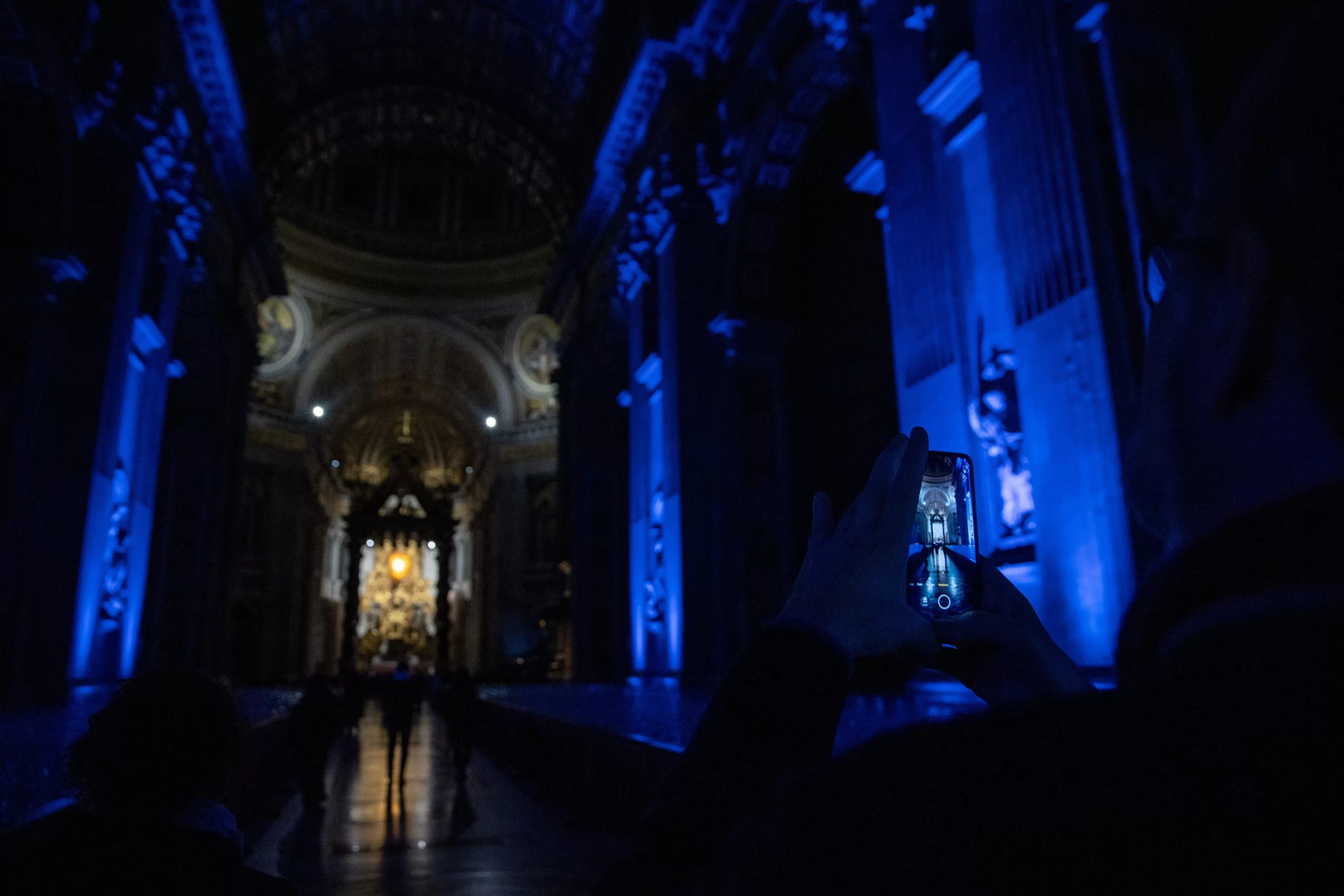 A visitor captures the dramatically lit central nave of St. Peter's Basilica on their phone during the 'White Night' celebration, Feb. 16, 2025. Credit: Daniel Ibáñez/CNA