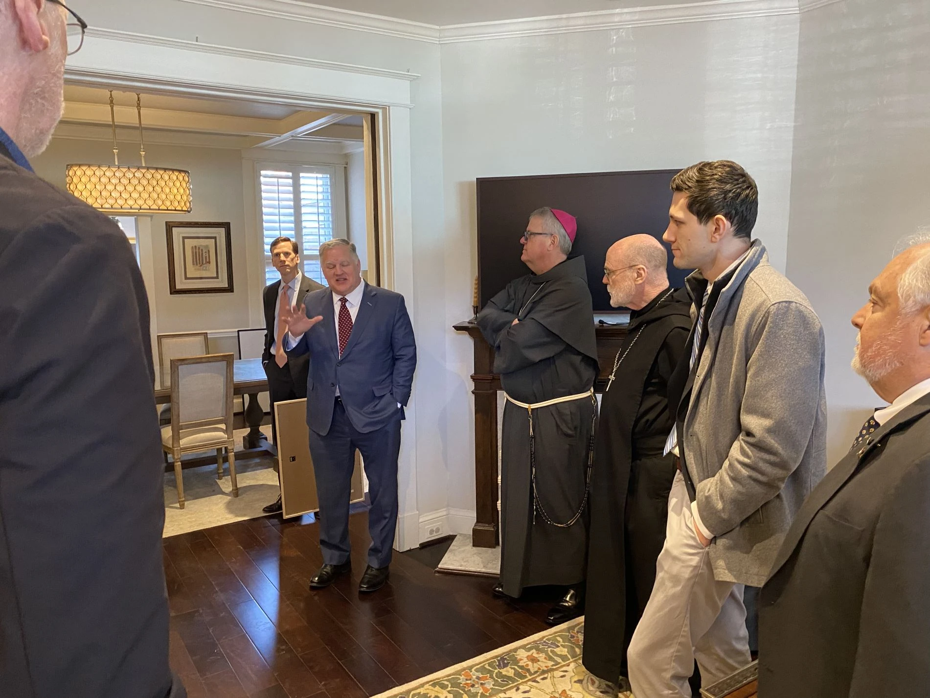 Phil Brach, vice president of college relations at Belmont Abbey College, chats with Abbot Placid Solari, Charlotte Bishop Michael Martin, and other college leadership, guests, and friends during a tour of the Belmont House on Feb. 28, 2025. Credit: Belmont Abbey College