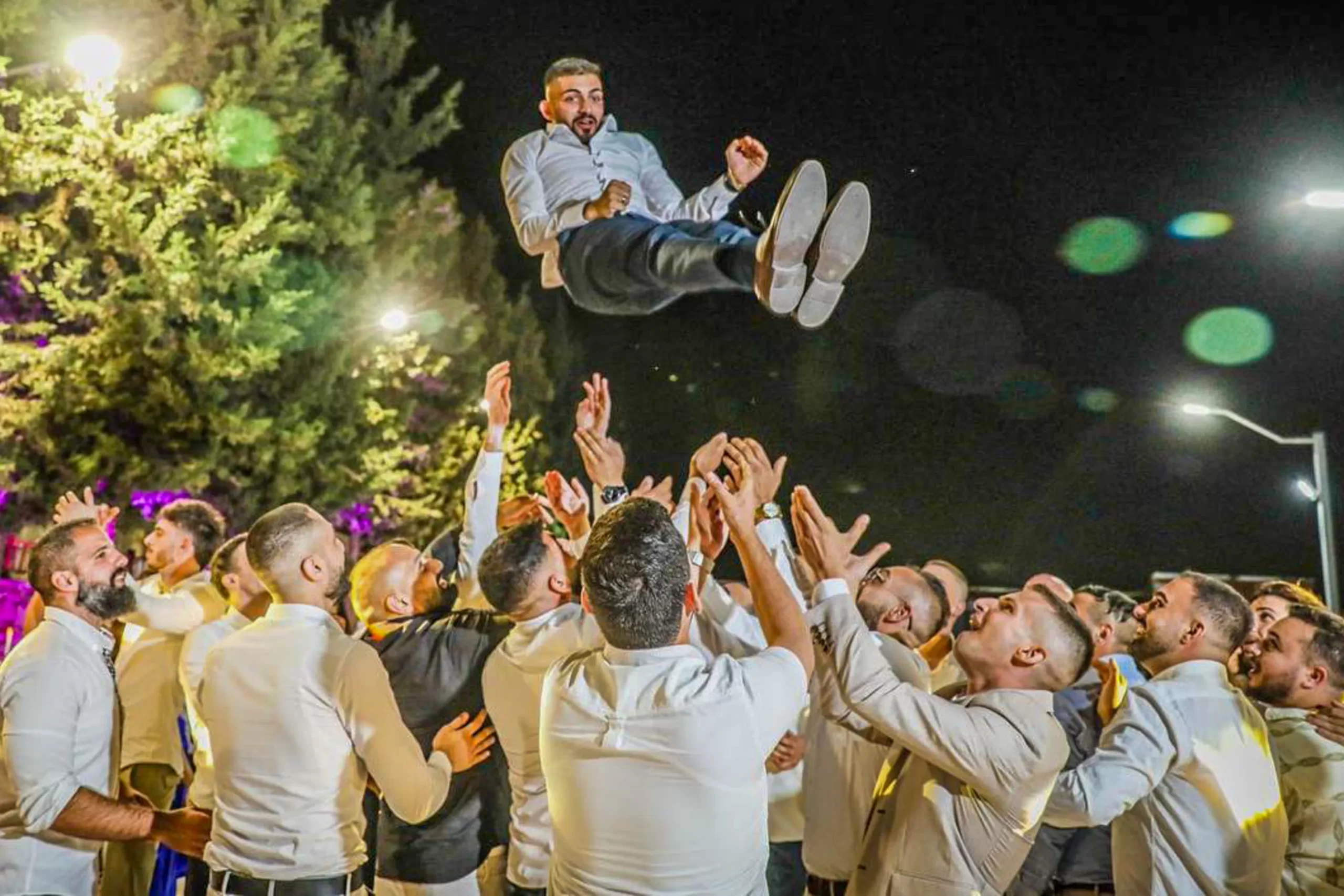 Elias Al Arja is lifted into the air by his friends during the engagement party with Sabeen Rahil. Both from Bethlehem, they met for the first time in 2020 through the “Leo Club,” the youth branch of the Lions Club, an organization that promotes events and fundraising activities to support charitable works and people in need. Credit: Photo courtesy of Sabeen Rahil and Elias Al Arja