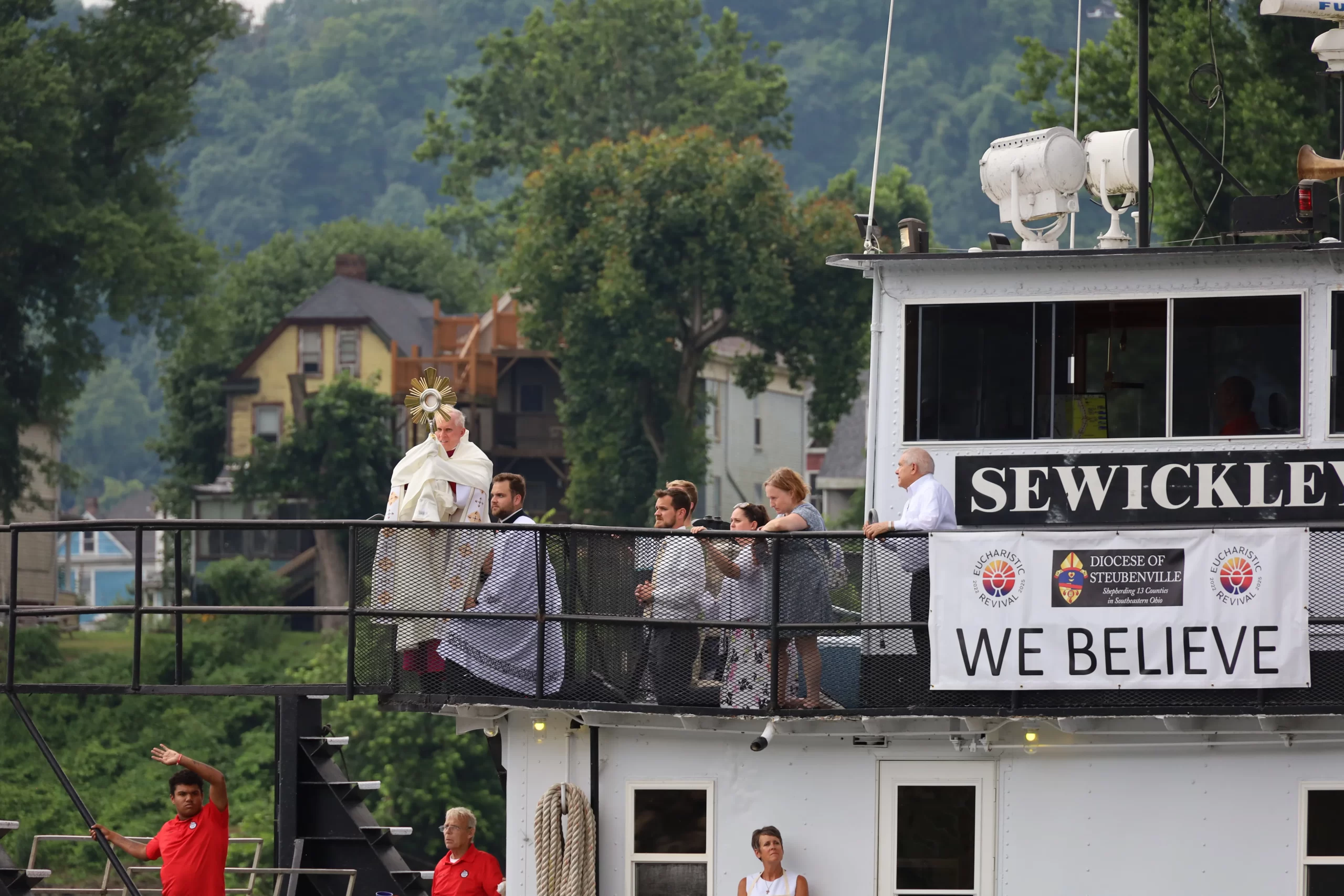 Father Roger Landry holds aloft the Blessed Sacrament aboard the vessel "Sewickley" on the Ohio River near Steubenville, Sunday, June 23, 2024. Credit: Colleen Rowan