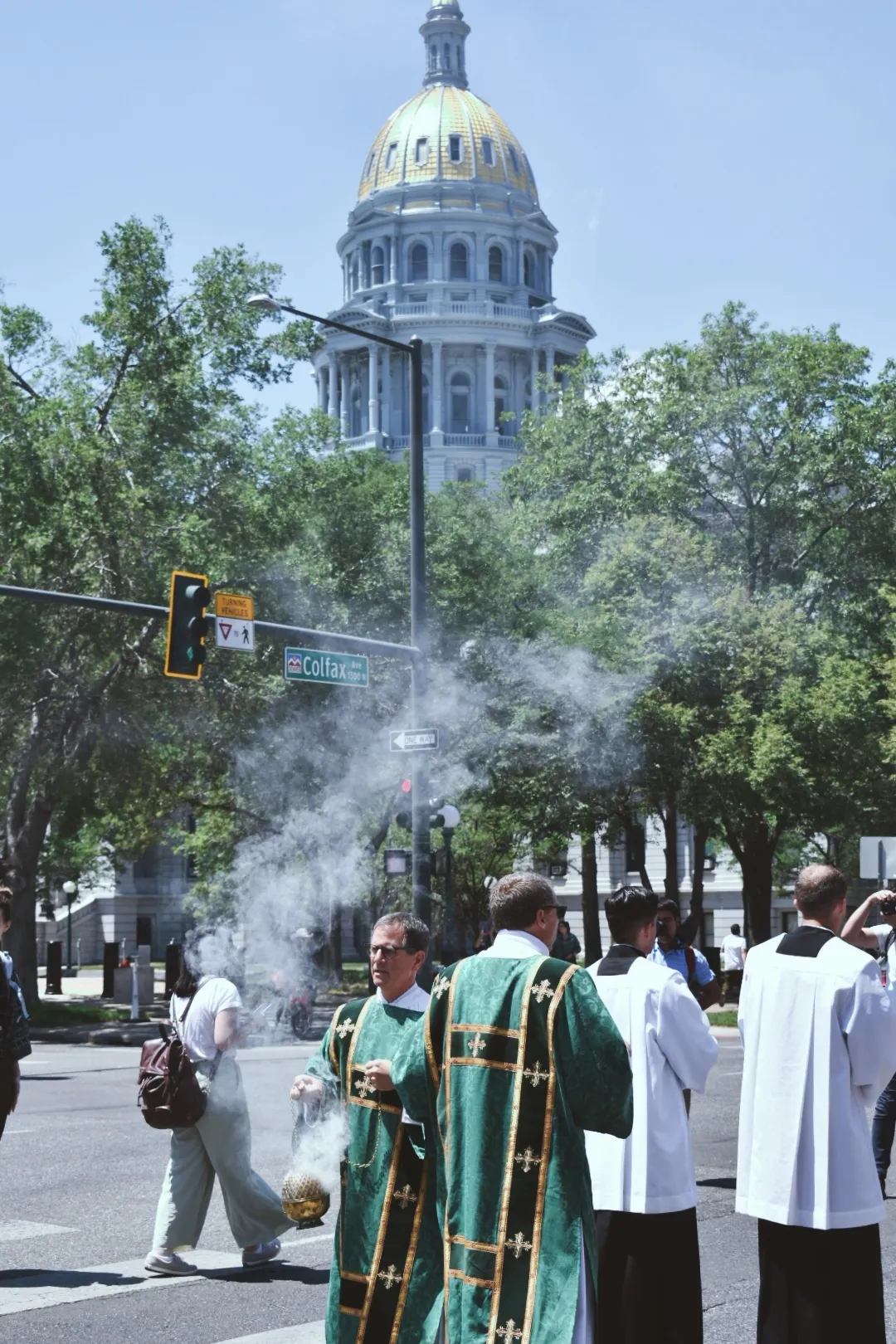 A priest spreads incense during the Eucharistic procession, facing the monstrance, while another priest leads him in front of the Colorado state capitol on June 9, 2024. Credit: Kate Quiñones/CNA