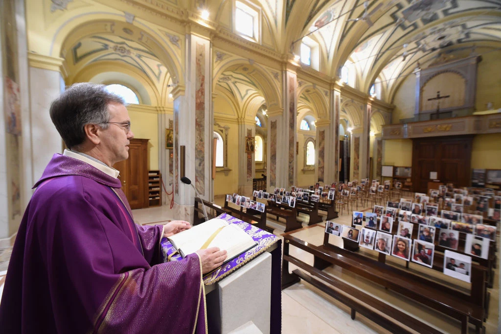 Father Don Giuseppe celebrates the Mass in front of portraits and selfies sent by the parishioners on March 17, 2020, in Robbiano, Italy. Credit: Pier Marco Tacca/Getty Images