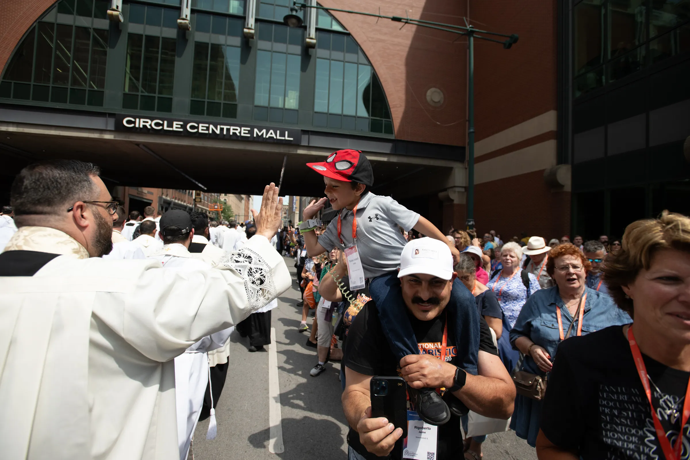 A young boy high fives a priest during the Eucharistic Procession through downtown Indianapolis. Credit: Jeffrey Bruno