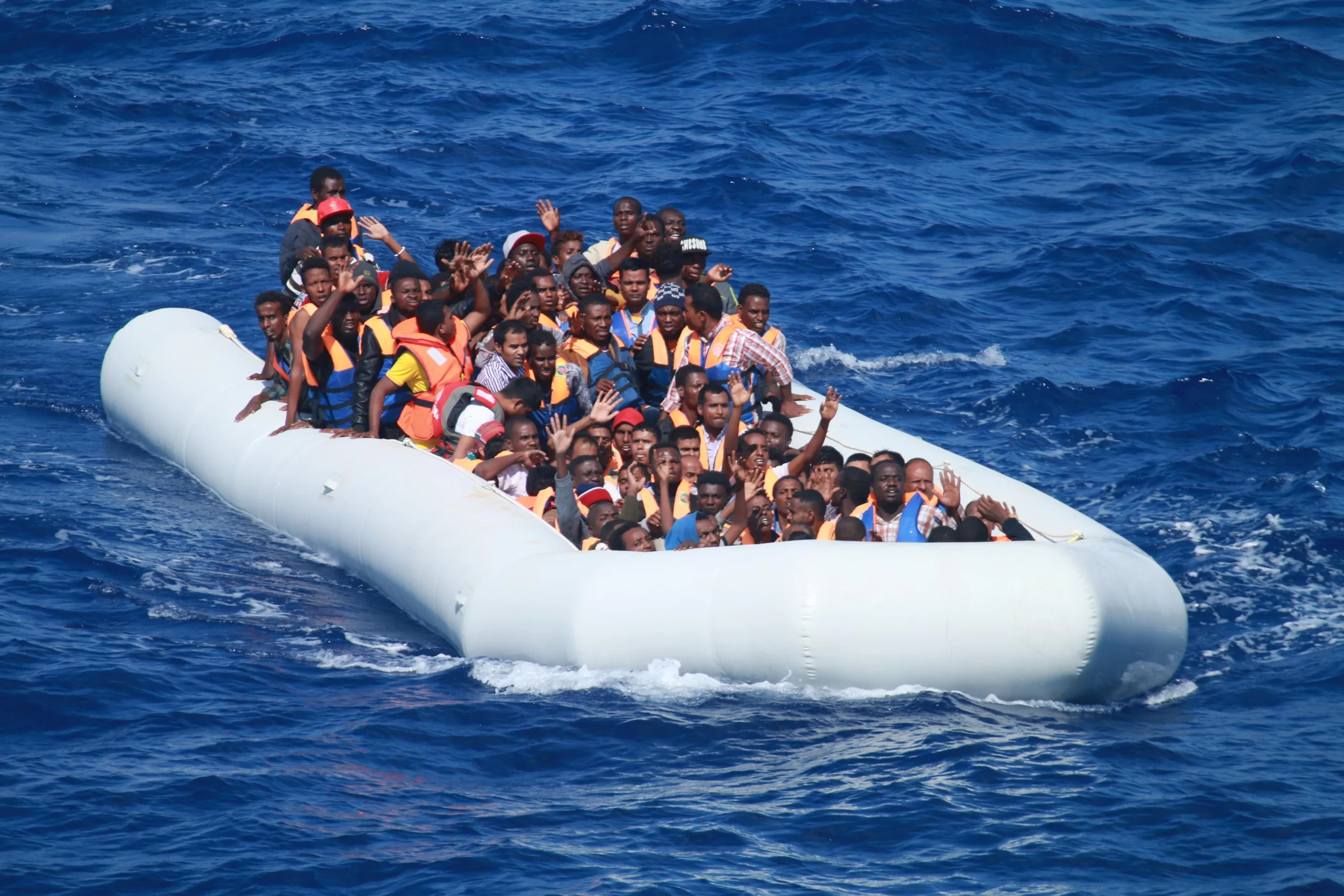 Migrants aboard an inflatable vessel in the Mediterranean Sea approach the guided-missile destroyer USS Carney in 2013. Carney provided food and water to the migrants aboard the vessel before coordinating with a nearby merchant vessel to take them to safety. Credit: Commander, U.S. Naval Forces Europe-Africa/U.S. 6th Fleet, Public domain, via Wikimedia Commons