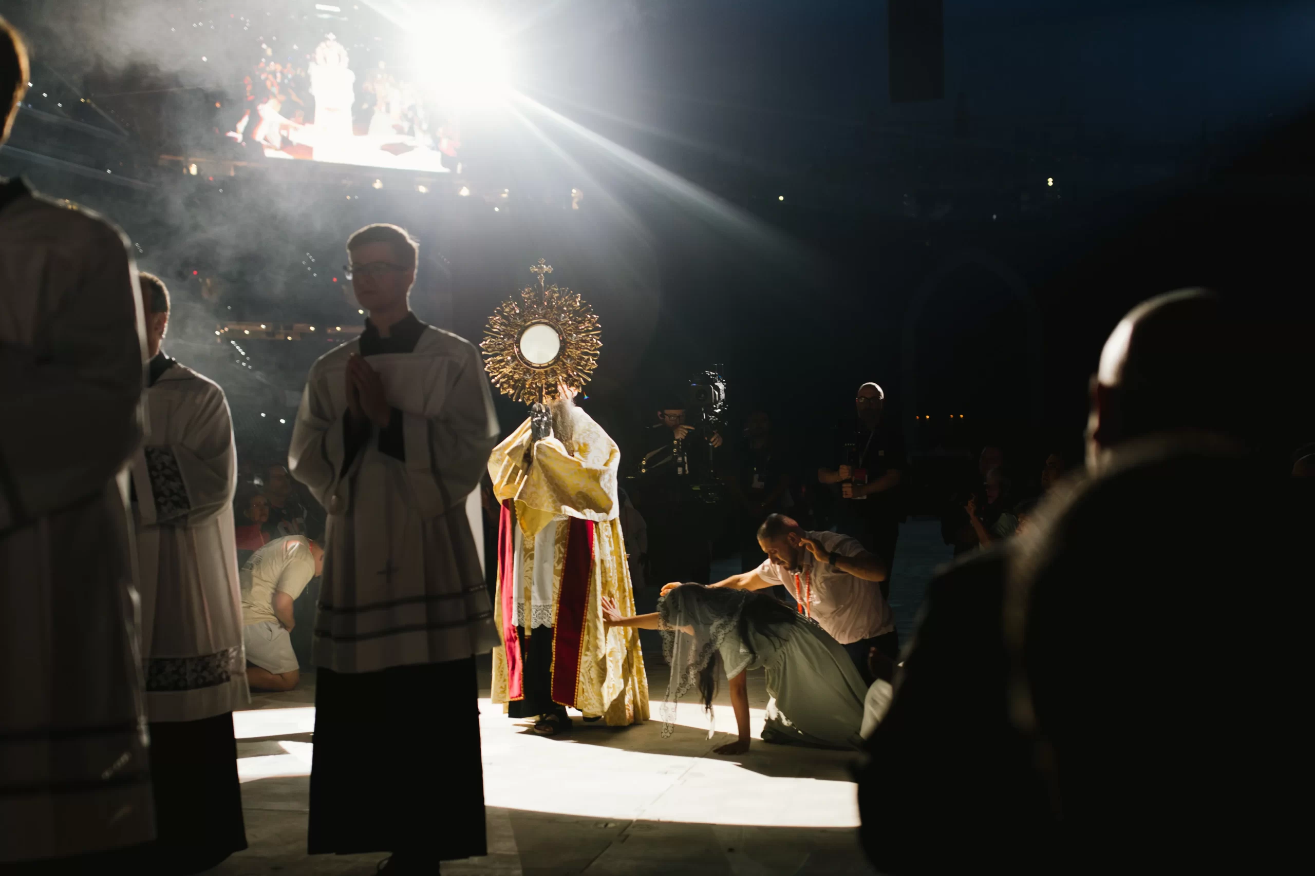 Attendees kneel and reach for the monstrance as it passes by them during a procession at the National Eucharistic Congress in Indianapolis. Credit: Jacob Bentzinger in partnership with the National Eucharistic Congress