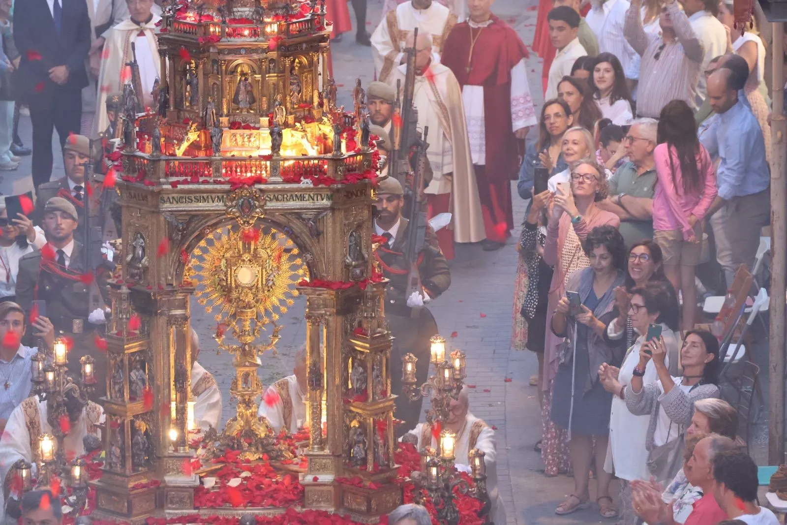 After a large group of vested priests processes down the street during the annual Corpus Christi procession in Valencia, Spain, a group of sacristans follow, creating a cloud of incense. Jesus then arrives as flower petals rain down on the monstrance, thrown by the faithful gathered on their balconies and those lining the streets. June 2, 2024. Credit: Miriam Sancho