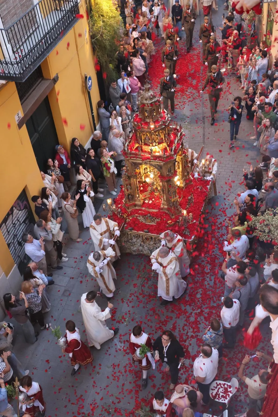 After a large group of vested priests processes down the street during the annual Corpus Christi procession in Valancia, Spain, followed by a group of sacristans creating a cloud of incense, Jesus arrives as flower petals rain down on the monstrance, thrown by the faithful gathered on their balconies and those lining the streets. June 2, 2024. Credit: Miriam Sancho